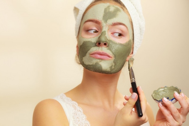 viso donna applica maschera argilla verde pennello ciotola