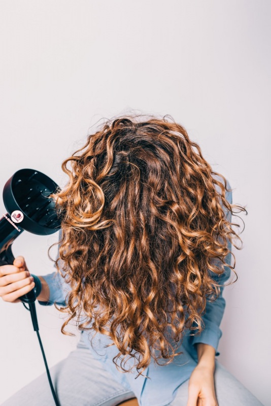 donna asciuga i capelli ricci con phon e diffusore