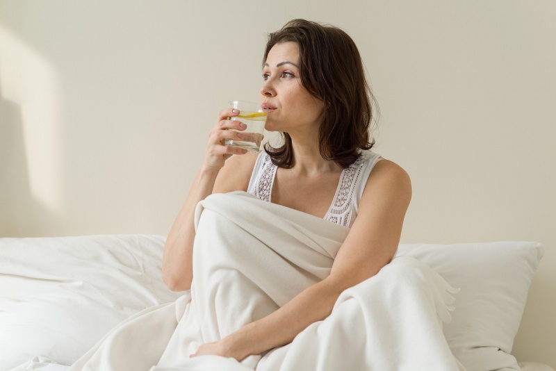 donna beve acqua e limone letto mattino