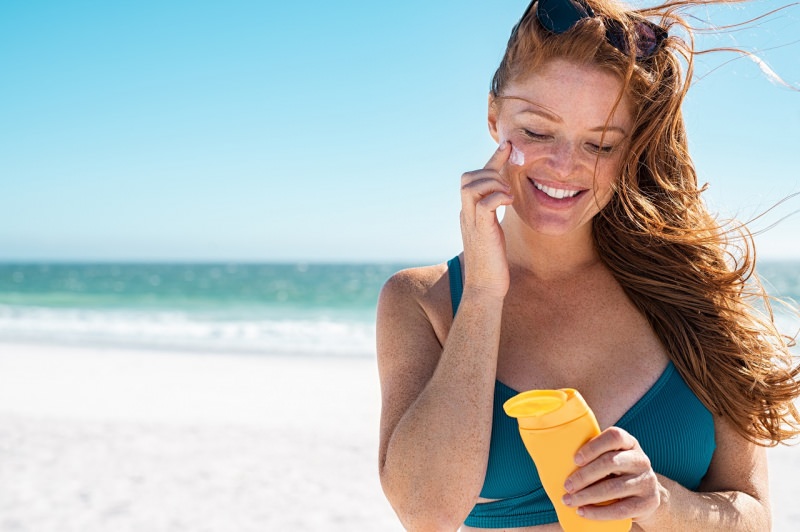 protezione solare bella donna sorriso tipo nordico fototipo 2 lentiggini capelli rossi mare estate crema