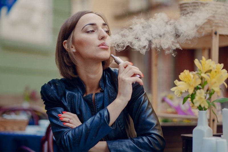 donna svapa sigaretta elettronica al bar vapore e-cig