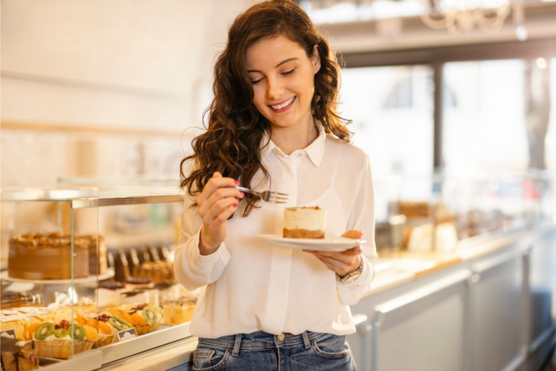 dolci tentazioni giovane donna capelli castan sorridente denti bianchi sorriso camicia bianca jeans denim tiene piatto con dolce in mano