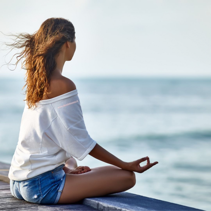 relax donna capelli lunghi castani di spalle vista mare meditazione posizione yoga