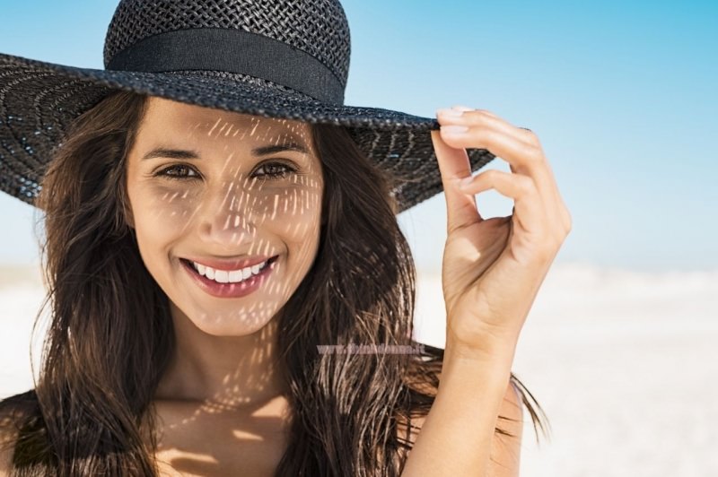 viso donna sorridente con cappello paglia spiaggia estate