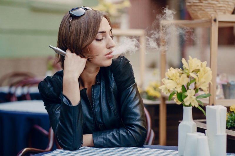 donna seduta al bar svapa e-cig sigaretta elettronica