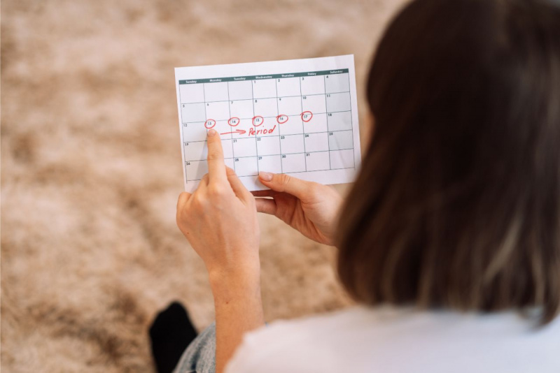 calendario ciclo mestruale in mano a donna di spalle