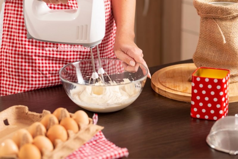 donna grembiule qudretti rosso bianco preparazione torta sbattitore uova ciotola vetro