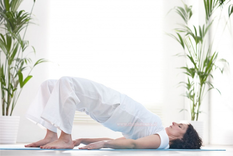 esercizio fisico ponte donna sdraiata su tappeto fitness a casa soggiorno piante verdi