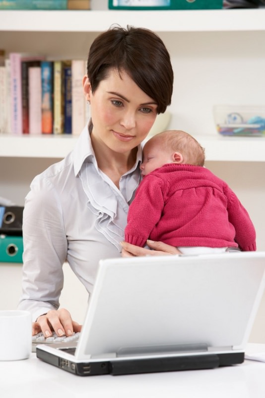 donna mamma neonato in braccio lavora con laptop casa libri