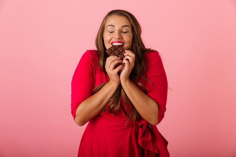 donna sovrappeso abito rosso mangia tavoletta cioccolato