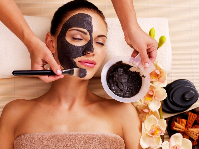 maschera viso al cioccolato su viso donna in relax applicato con pennello fiori orchidea