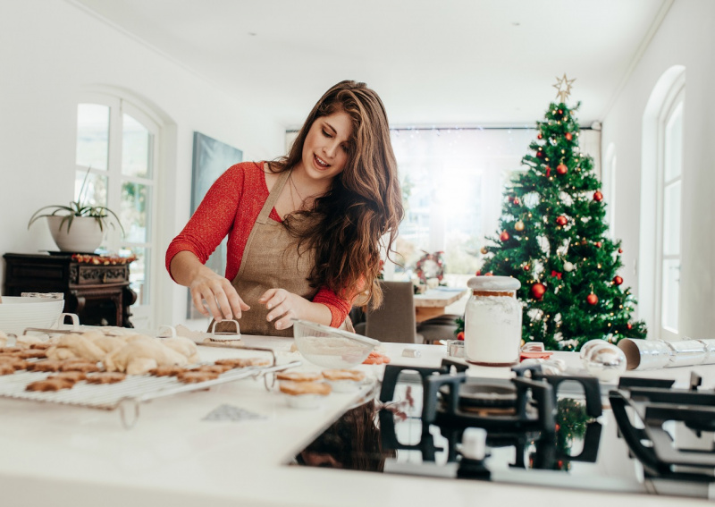 giovane bella donna mamma casalinga prepara biscotti natalizi albero di Natale piano cottura
