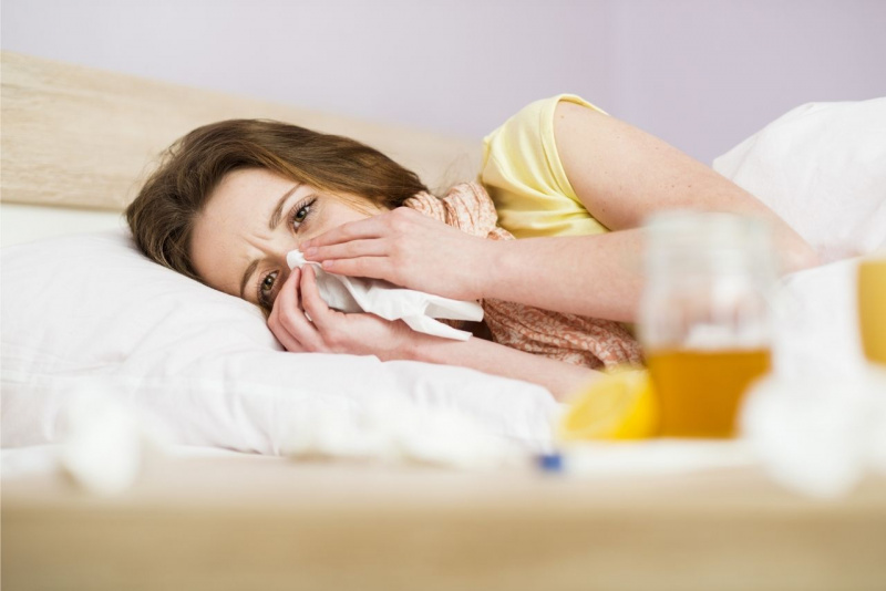 donna sdraiata a letto raffreddore inflenza fazzoletto