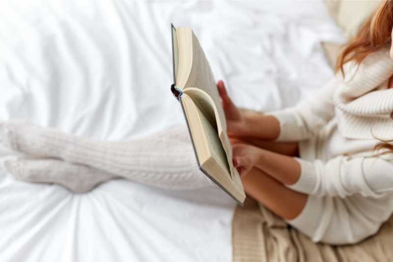 lettura libro romanzo sdraiati sul letto lenzuola calze lana bianca