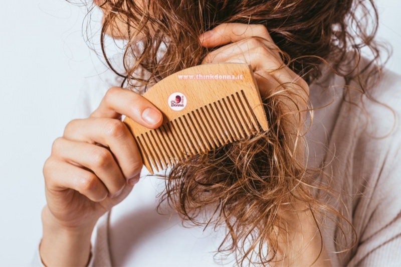 donna pettina i suoi capelli ricci con un pettine di legno