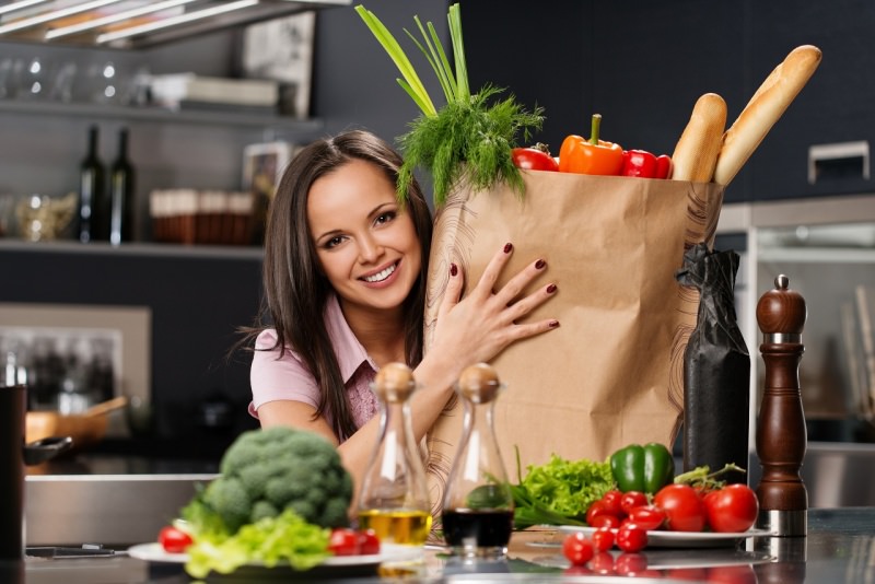 donna sorridente sacco spesa in cucina pane frutta e verdure