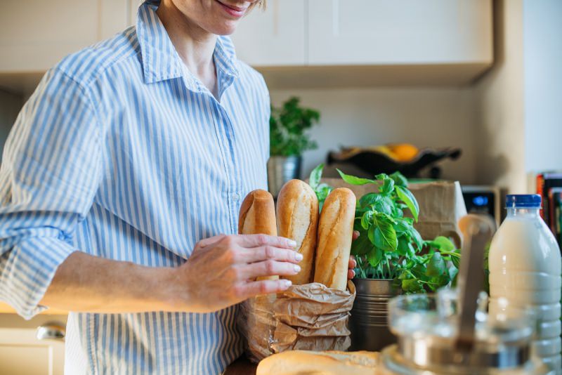 donna sistema spesa in cucina sacco pane verdure