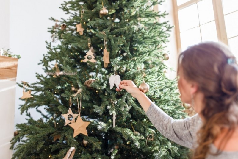 donna sta decorando albero di natale in stile minimal scandivano decorazioni legno