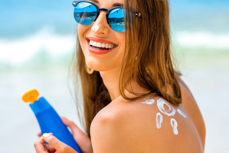 viso donna sorridente lozione protezione solare a forma di sole sulla spalla sorriso 