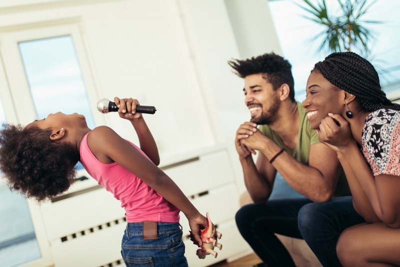 pap e mamma guardano la figlia con microfono canta karaoke