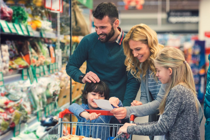 uomo sorridente con barba pap con donna bionda mamma figlia e figlio si divertono a fare la spesa