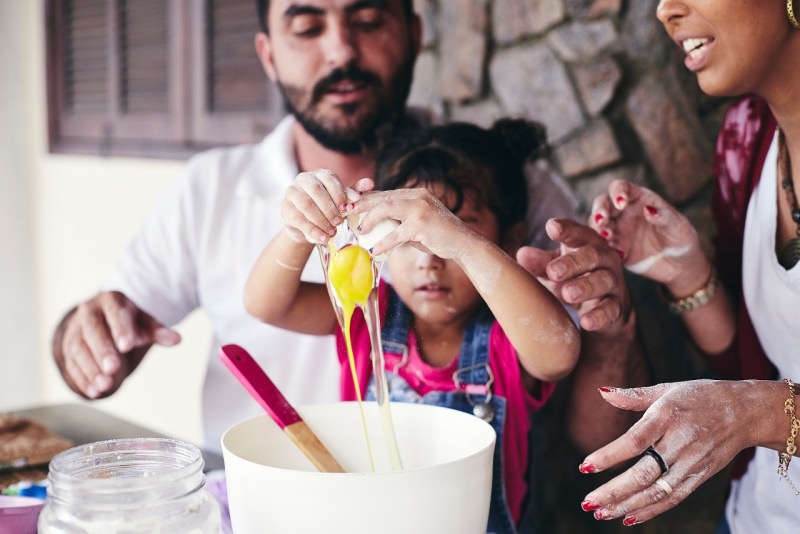 famiglia felice pap e mamma aiutano figlio bambino a cucinare 