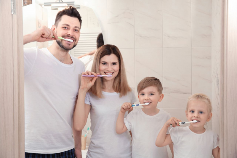 uomo pap donna mamma figlio figlia usano spazzolino denti sorrisi prevenzione dentale famiglia