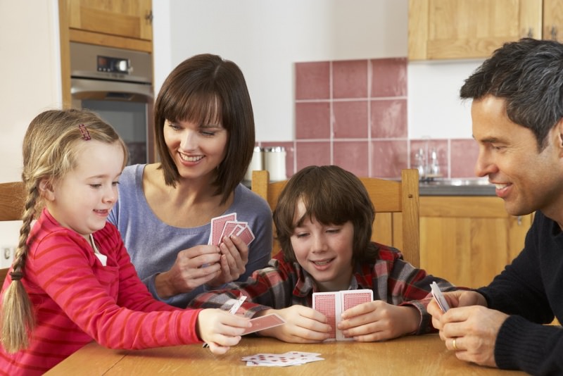 famiglia felice bambini gioca a carte in cucina