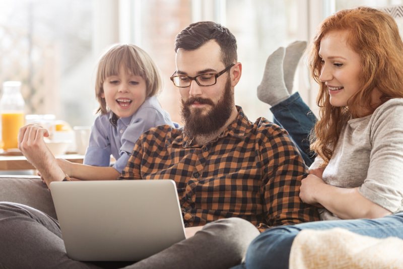 famiglia felice in casa sul divano guarda laptop notebook