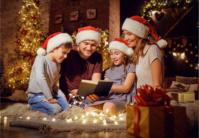 pap uomo legge libro mamma donna sorridente capelli biondi figli bambino bambina lettura sorrisi decorazioni Natale atmosfera magico