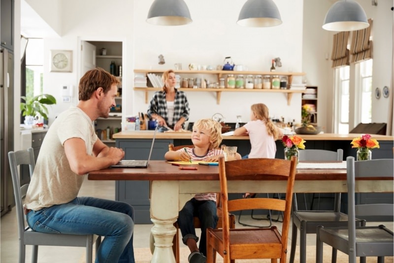 famiglia serena pap uomo seduto tavolo figlio bambino mamma donna prepara cucina figlia compiti a casa sorrisi