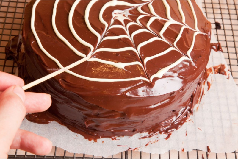 decorazione ragnatela di cioccolato bianco disegnata con stuzzicadente su torta halloween cioccolato fondente