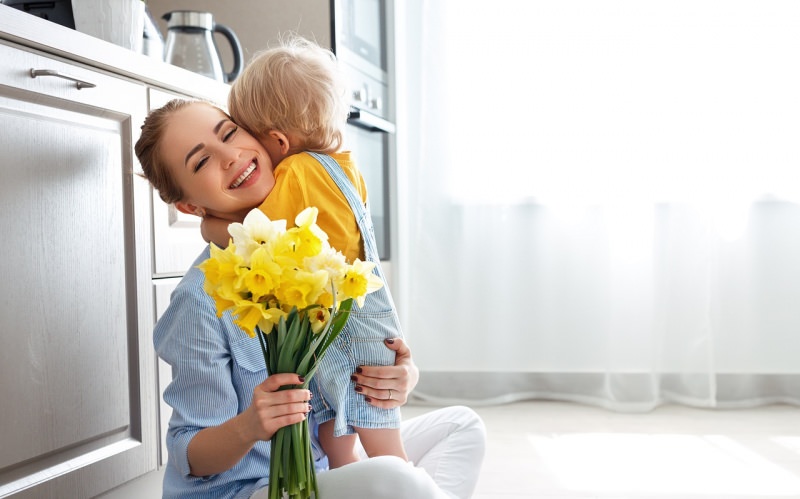 bambino biondo abbraccio mamma auguri festa della mamma fiori narcisi bianco giallo