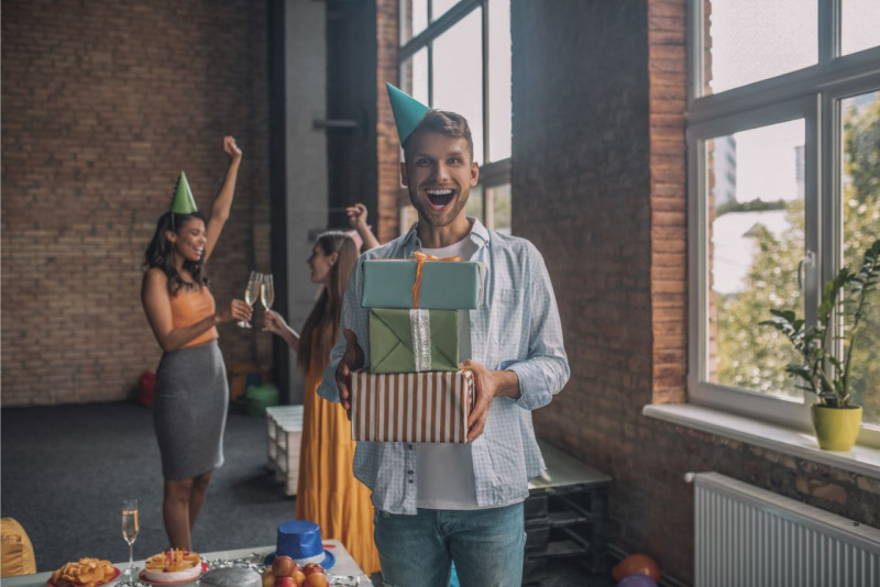 uomo felice tiene in mano tanti pacchi regalo festa compleanno amiche brindisi 