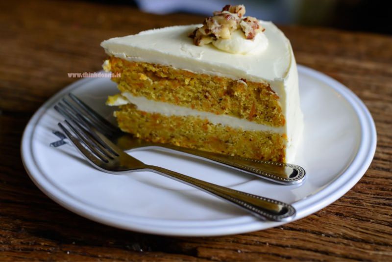 fetta di torta di carote e noci con crema al mascarpone piatto bianco forchette