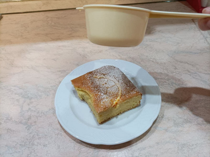 primo piano fetta torta all'arancia con spolverata di zucchero a velo setacciato colino