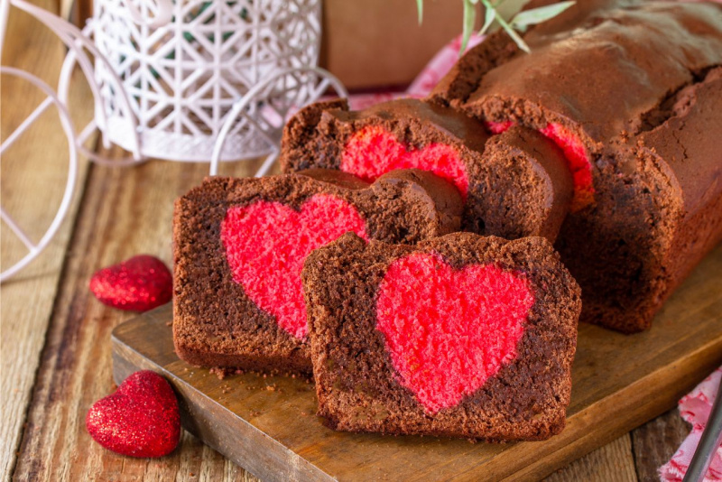 fetta plumcake al cacao con centr a forma di cuore rosso su tagliere legno cuori rossi 