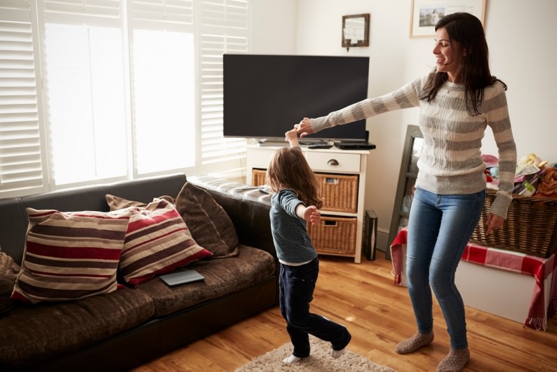 mamma e figlia ballano in soggiorno a casa tv divano