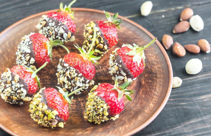 vassoio con fragole fresche ricoperte con cioccolato fondente e granella di mandorle e nocciole