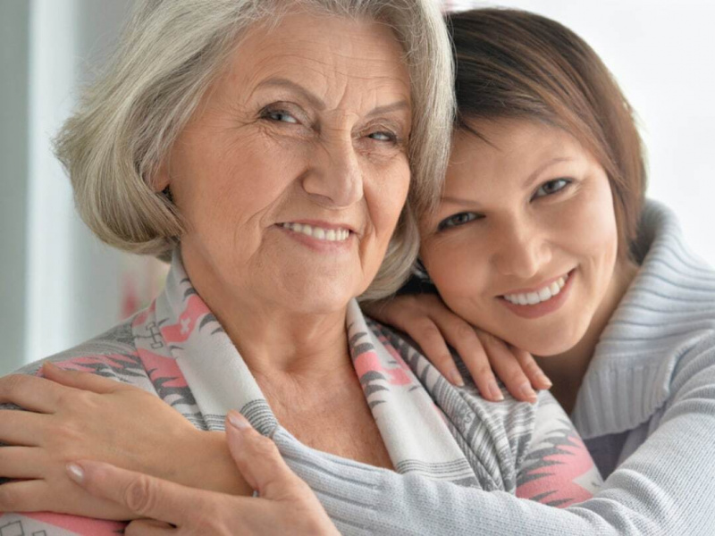 figlia adulta abraccia mamma anziana sorrisi