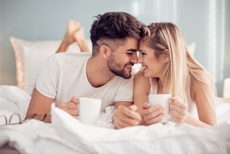 giovane coppia innamorati a letto sorridono a letto