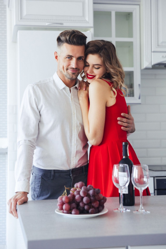 giovane coppia capodanno donna abito vestito rosso uomo jeans piatto uva calici vino