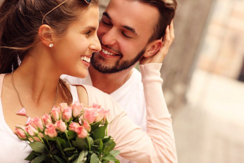 giovane coppia sorrisi uomo donna romantici bouquet mazzo fiori rose rosa