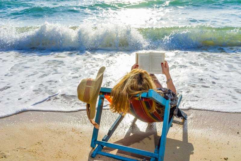 donna legge libro al mare onde sole cappello estate relax