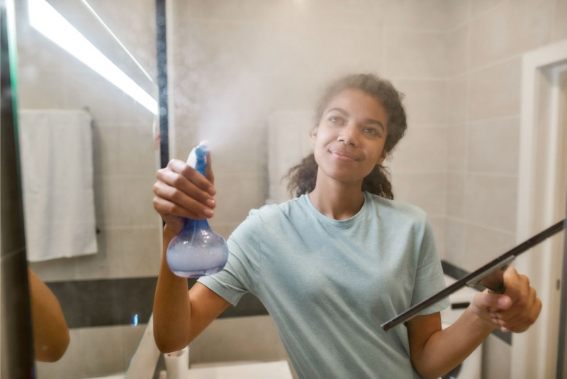 donna spruzza vetro doccia e asciuga con spatola asciuga vetri