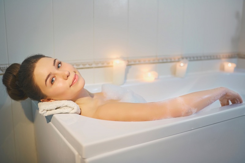 bella donna si rilassa nella vasca da bagno relax candele 