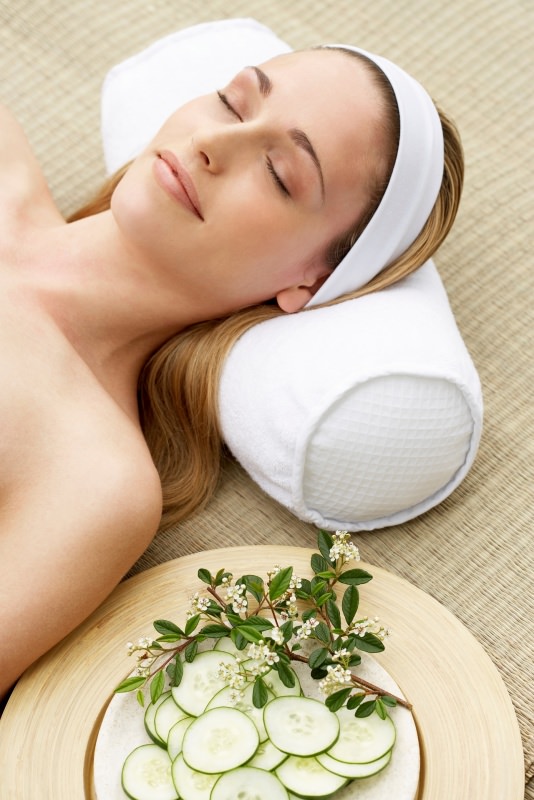 Viso donna bellissima testa su cuscino fettine cetriolo su piatto relax