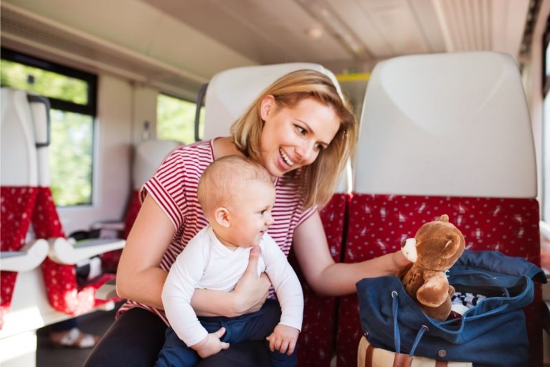 giovane mamma viaggia in treno con figlio bambino piccolo borsa peluche