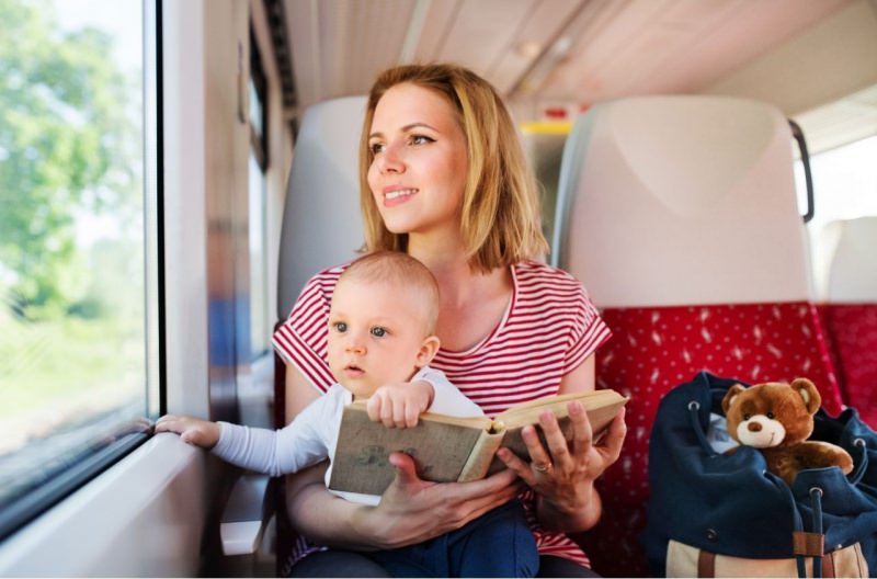 giovane donna viaggia in treno con figlio piccolo neonato libro borsa peluche orsetto