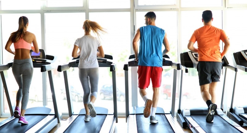 uomini e donne in palestra corrono sul tapis roulant